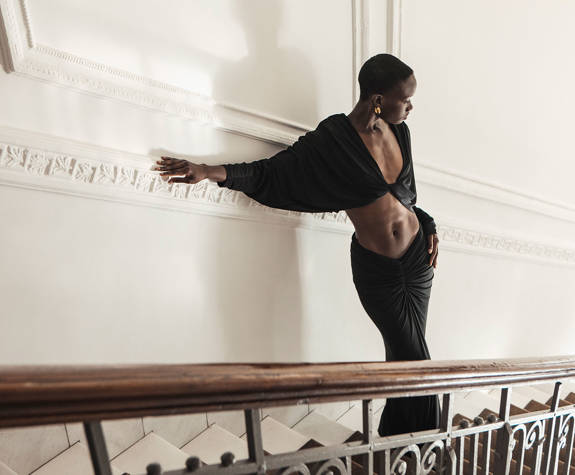 Fashionably dressed guest in elegant black attire posing on ornate staircase at Excelsior Hotel