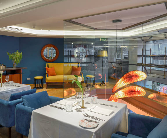 Professional Mezzanine setup at The Excelsior Hotel with blue velvet seating, white linen tables, contemporary glass accents, and a cozy yellow sofa area, ideal for business meetings